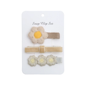 Détail d'un ensemble de trois barrettes à marguerites avec broderie et velours sur carte