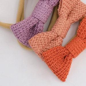 Detail view of three soft knitted bow headbands in pink and orange for baby girls