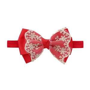 Detailed view of red lace bow baby headband with gold embroidery and elastic nylon band