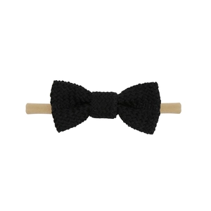 Detail of a black knitted bow on a soft khaki elastic nylon headband for babies