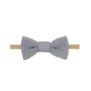 Detail showing the soft grey knitted bow texture on a khaki elastic nylon baby headband