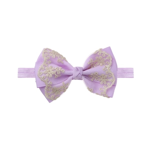 Detailed macro view of purple baby headband featuring gold lace floral embroidery accents