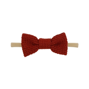 Detail of dark red knit cotton bow with soft beige nylon elastic headband for infants