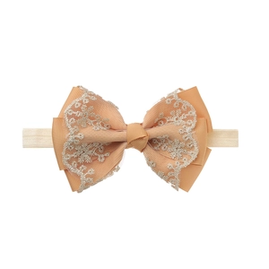 Detail of baby lace bow headband featuring apricot ribbed ribbon and golden embroidery