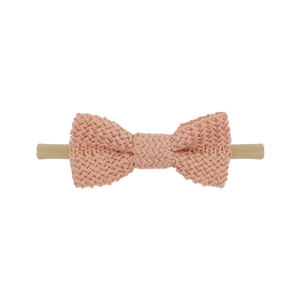Detailed close-up of coral pink knitted cotton bow with elastic nylon headband for babies