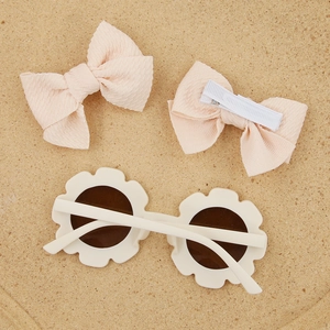Détails des barrettes nœuds roses et lunettes fleur beige sur un support en liège