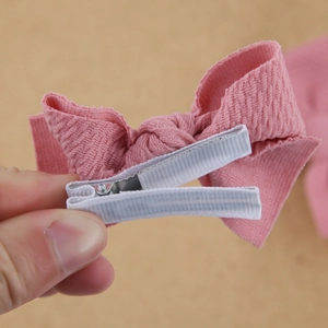Gros plan sur la barrette nœud rose avec texture en maille et pince en métal gainée