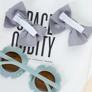 Détail de lunettes de soleil fleur menthe avec barrettes à nœud gris pour enfants