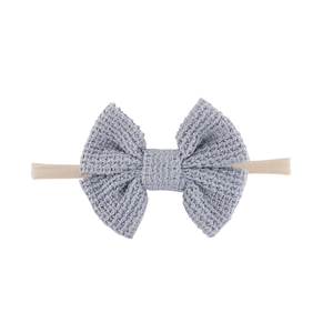 Detail einer hellblauen Strickschleife auf einem weichen Nylon-Babystirnband