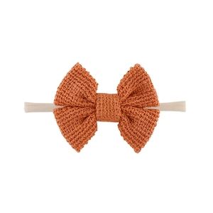 Detailaufnahme der handgestrickten orangen Schleife auf weichem Nylon-Babystirnband