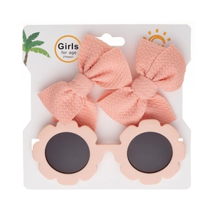 Gros plan de lunettes de soleil fleurs roses et deux barrettes nœuds sur carte de vente