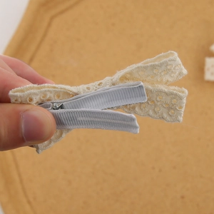 Détail d'une barrette à cheveux avec noeud en dentelle et clip métallique robuste au dos