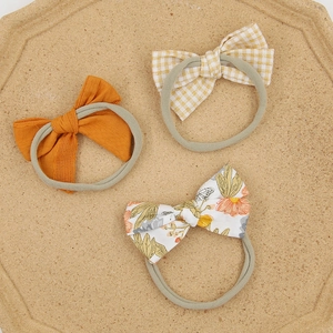Detailed set of three soft baby bow headbands with floral, checkered, and solid patterns