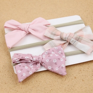Detail view of baby headband set with solid, plaid, and floral bows on display card