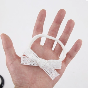 Détail d'un bandeau blanc doux en dentelle avec nœud pour bébé et motif floral élastique