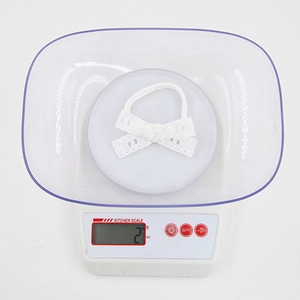Gros plan du bandeau en dentelle blanche sur une balance montrant le poids ultra-léger de 2g