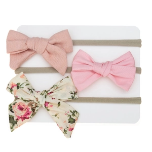Detailed set of three baby headbands with floral prints and soft bows on white paper