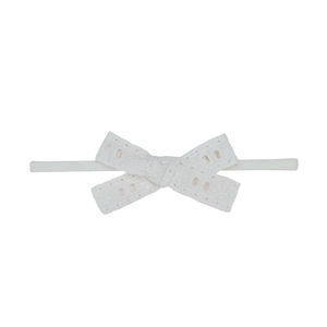 Détail du bandeau pour bébé avec nœud en dentelle et broderie anglaise couleur ivoire