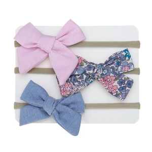 Detailed view of three-piece set baby bow headbands in floral, pink, and denim textures