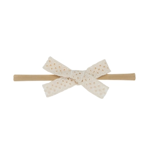 Vue détaillée du bandeau bébé en dentelle beige avec nœud et nylon élastique doux