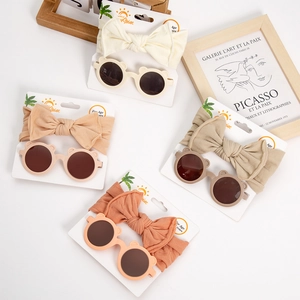 Flat lay of baby bow headbands and bear ear sunglasses in four warm earth tones