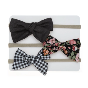 Detailed view of baby bow headbands featuring floral, solid, and checkered patterns on a card
