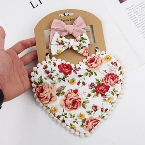 Detail of floral baby bib and bow headband set on a display card for Valentines