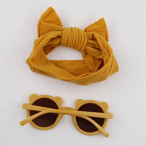 Close-up of baby yellow bear-ear sunglasses and a large bow elastic nylon headband