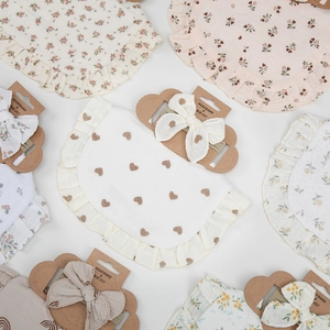 Detailed flat lay of ruffle baby bibs and matching bow headbands with floral patterns