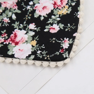 Detail of floral printed fabric bib with white pom-pom lace trim and rose pattern