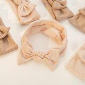 Elastic baby headband set featuring soft ribbed fabric and a large bow in nude pink tones