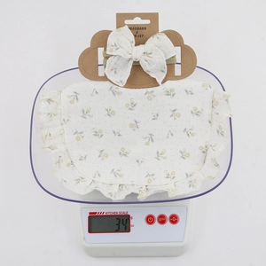 Detail of floral cotton baby bib and headband set on a scale weighing 34 grams