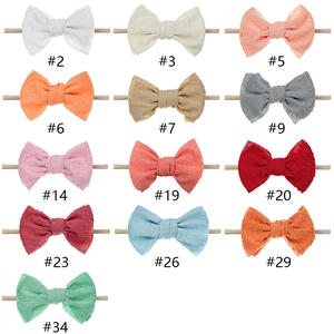 Collection of 13 colorful stretch nylon baby headbands with textured jacquard bow tie dots