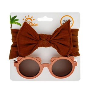 Detail of baby accessory set with brown bow headband and pink bear ear sunglasses