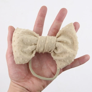 Detailed view of handmade cream nylon headband with textured jacquard dots and soft bow