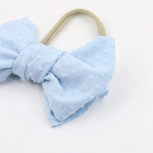 Detail of light blue bow headband with textured dots on a soft nylon elastic band