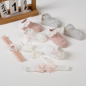 Flat lay of pink white and grey baby socks and floral headbands set on beige background