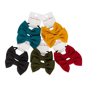 Detail of five pairs of textured bubble fabric bow hair ties on white display cards