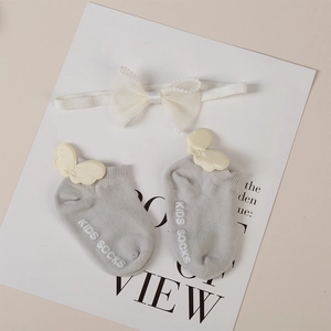 Detail of infant non-slip cotton socks with yellow bows and matching pearl headband