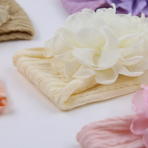 Dettaglio ravvicinato di un fiore in chiffon crema su una fascia elastica per neonati