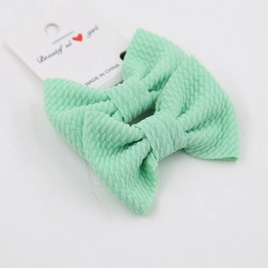 Detail of mint green ribbed bow hair clips on a decorative paper card packaging