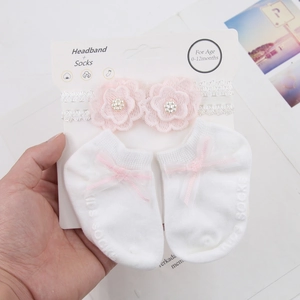 Detailed view of white lace baby headband and socks set with pink flowers and non-slip dots