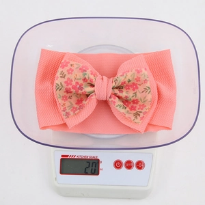 Pink elastic ribbed headband for girls featuring a large floral print bow, 20g weight