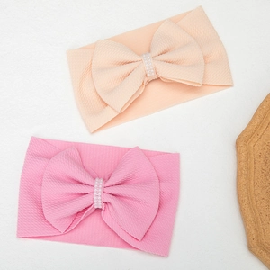 Detail of pink and beige baby headbands with large bows and pearl bead centers