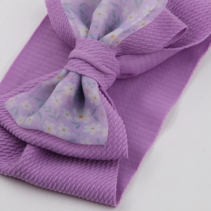 Detail of purple elastic baby headband with floral print organza bow and soft texture