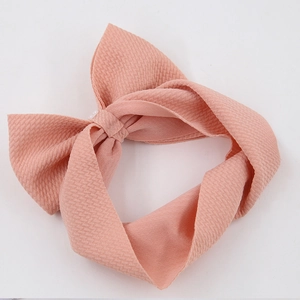 Close-up of peach fabric bow headband featuring delicate pearl accents and textured fabric
