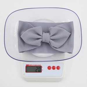 Grey waffle knit bow headband for infants showing 20g lightweight on scale