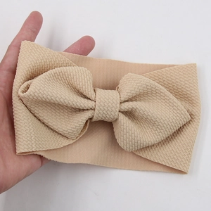 Detail of soft apricot waffle fabric baby headband with large bow held in hand