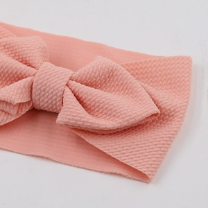 Close-up of baby headband featuring pink waffle knit fabric and a classic bow design