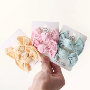 Detailed view of handmade knitted lace bow hair clips in yellow, pink, and cyan colors